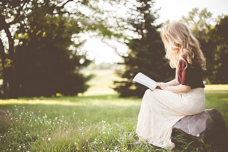 A woman sitting in the garden and reading a book